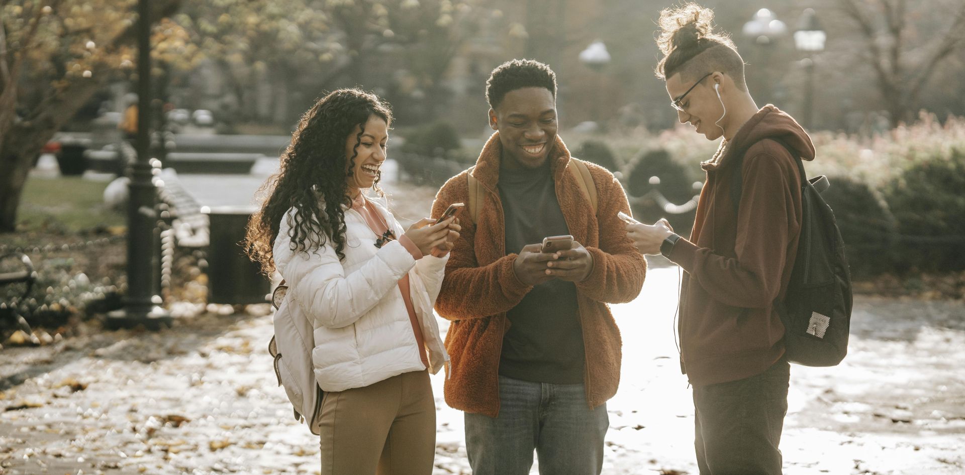 Multiracial positive male and female students using smartphones in city park