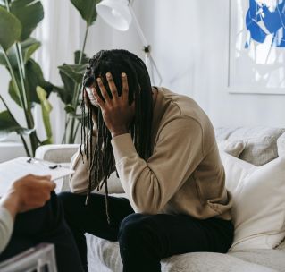 Stressed black man with dreadlocks in psychological office