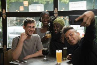 Happy multiethnic friends taking selfie on smartphone in cafe