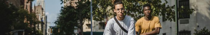 Full body of trendy active multiethnic male teens in stylish outfits balancing on skateboards during outdoor training in New York