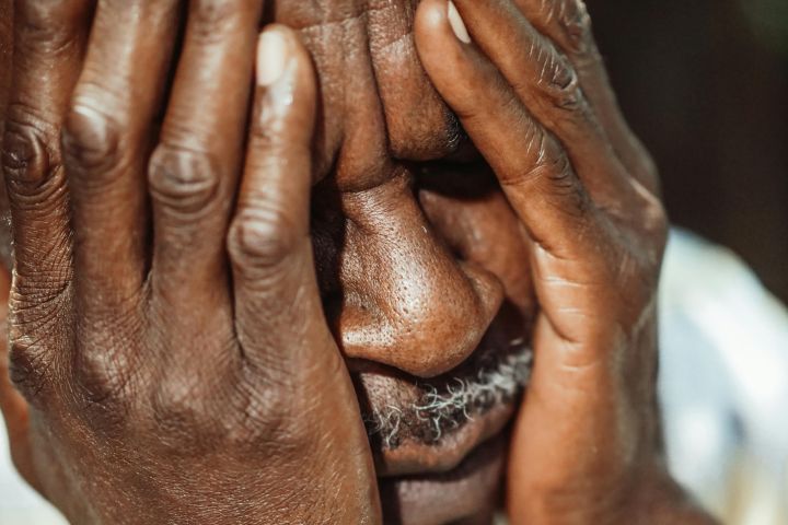 Man in White Shirt Covering His Face